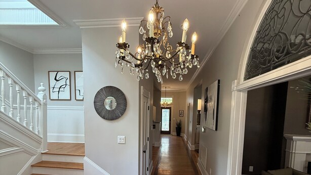 A grand hallway with a chandelier, wooden stairs, and a fireplace. - Charming & Spacious Historic Charlotte Home- in the heart of the city (Charlotte)