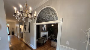 A hallway with wooden flooring, a chandelier, and a decorative wall arch. - Charming & Spacious Historic Charlotte Home- in the heart of the city (Charlotte)