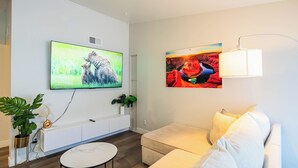 A modern living room with a flat-screen TV, a sofa, a coffee table, and a lamp. - Dwell 7003-3 (Scottsdale)