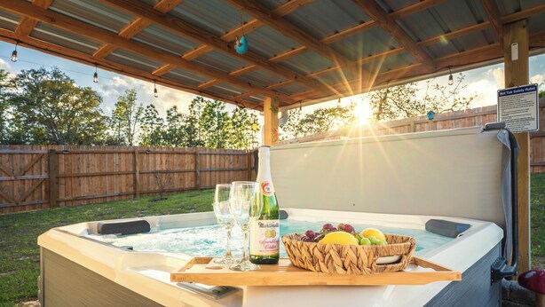 Ein Whirlpool mit einer Holzterrasse, ein Schild mit Sicherheitsregeln und eine Korb voller Obst und Flaschen.