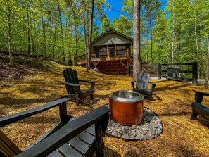 A cabin with a deck, surrounded by trees, and a fire pit with seating. - Hot Tub Cabin + Screened Porch | Red River Gorge (Beattyville)