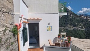 A balcony with a table set for dining, a chair, and potted plants. - GREEN NEST with a sea view (Amalfi)