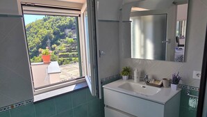 A bathroom with a large window, a sink, a mirror, and a potted plant. - GREEN NEST with a sea view (Amalfi)