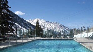 Une piscine à l’eau d’un bleu cristallin, entourée de chaises longues et avec une chaîne de montagnes en toile de fond.