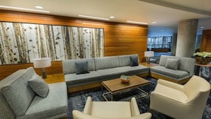 Un hall d’hôtel moderne avec un canapé gris, un fauteuil beige et une table basse.