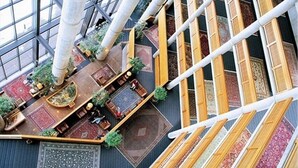 Un atrium doté de hauts plafonds, de grandes fenêtres et d’une variété de tapis et de meubles.