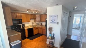 Una cocina con armarios de madera, un microondas negro y una campana extractora de acero inoxidable.