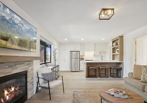 A modern kitchen with white cabinets, a stainless steel refrigerator, and a built-in island with bar stools. - Free Shuttle with free ski tunes/wax | Pool, Hot Tub, Tennis, Golf, Hike (Park City)