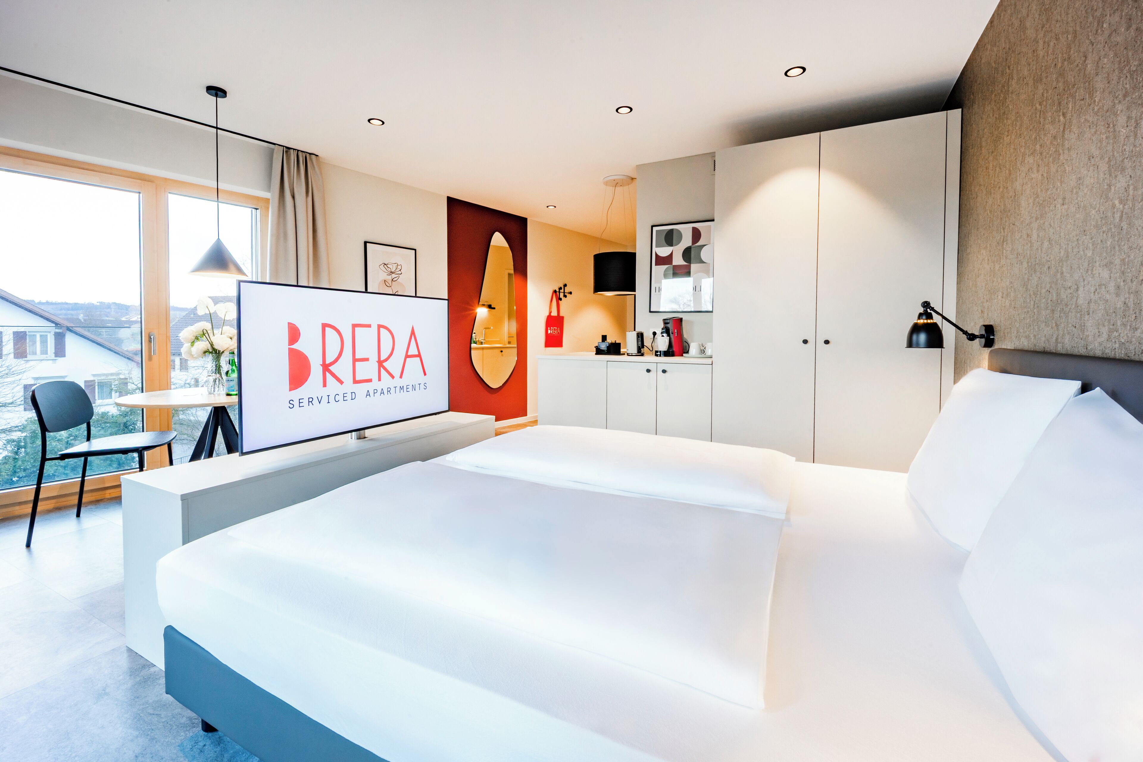 Un dormitorio moderno con una cama grande, un escritorio y vistas al exterior.