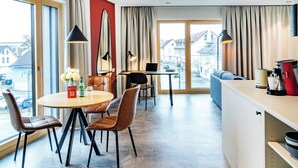 Habitación de hotel moderna con comedor, sofá y vista a la calle.