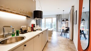 Una cocina moderna con un lavamanos grande, electrodomésticos en la encimera y un comedor con mesa y sillas.
