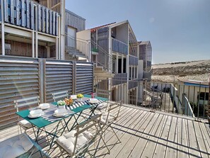 Een terras op het dak met een eethoek, inclusief een tafel, stoelen en uitzicht over de omgeving.