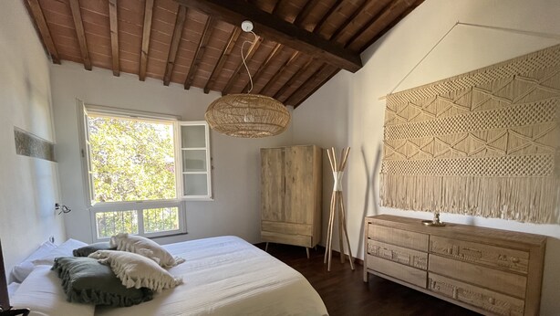 Une chambre à coucher avec un lit, une armoire en bois et une tapisserie accrochée au mur.