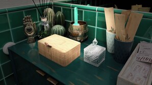 Un comptoir de cuisine sur lequel se trouvent divers objets, notamment un panier en bambou, un porte-bougie en verre, un vase décoratif et un gobelet en papier orné de motifs de feuilles.