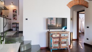 Un intérieur moderne avec un escalier, un meuble en bois et un téléviseur à écran plat fixé au mur.
