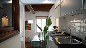 Une cuisine moderne avec un plan de travail noir, un évier en acier inoxydable et un luminaire suspendu.