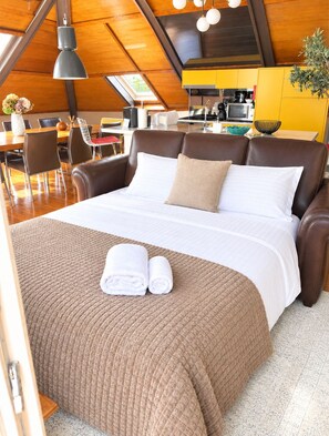 A hotel room with a large bed, a dining area, and a kitchen in the background. - Luxury Loft in Alfama with Balcony and River View (Lisboa)