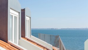 Een balkon met uitzicht op zee en een verre stadslijn.
