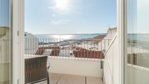 Een balkon met uitzicht op zee en gebouwen.