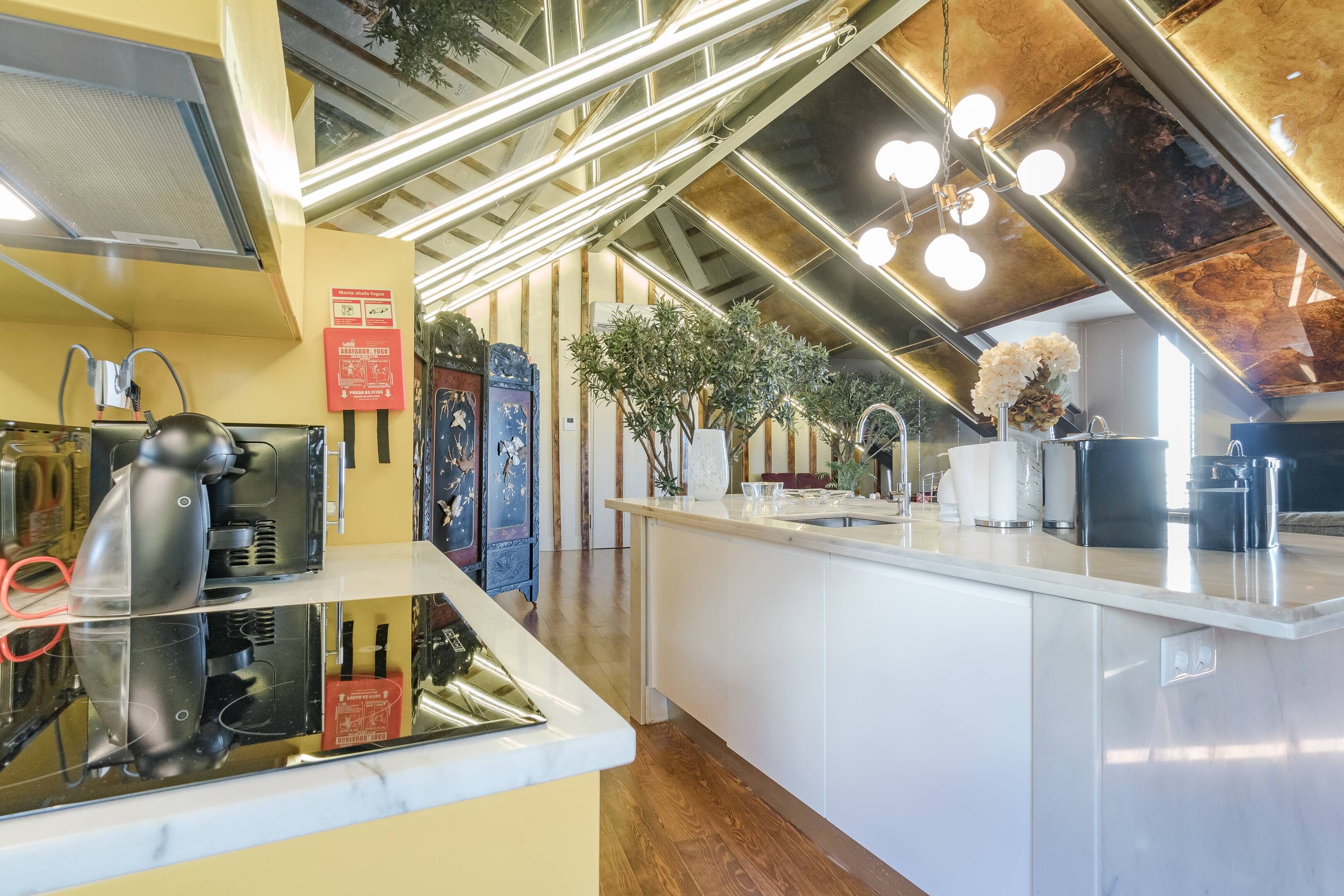 A modern kitchen with a marble countertop, stainless steel appliances, and a wooden floor.
