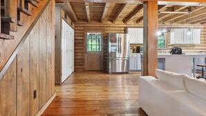 Un interior de madera con un sofá blanco, un refrigerador de acero inoxidable y pisos de madera.