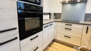A modern kitchen with white cabinetry, a black oven, a microwave, and a stainless steel range hood. - Duplex 6 persons with 2 parking spaces - Honfleur (Honfleur)