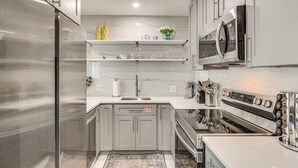 A modern kitchen with stainless steel appliances, marble countertops, and a built-in oven. - Las Olas Chic Apt w/ Patio & Free Parking (Fort Lauderdale)