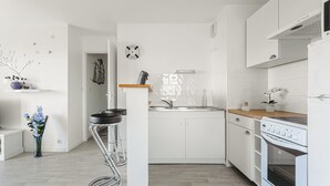 A modern kitchen with white cabinetry, a stainless steel sink, a built-in oven, and a wooden countertop.