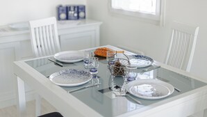 A dining table set with plates, glasses, and cutlery, with a basket containing pinecones and a candle.