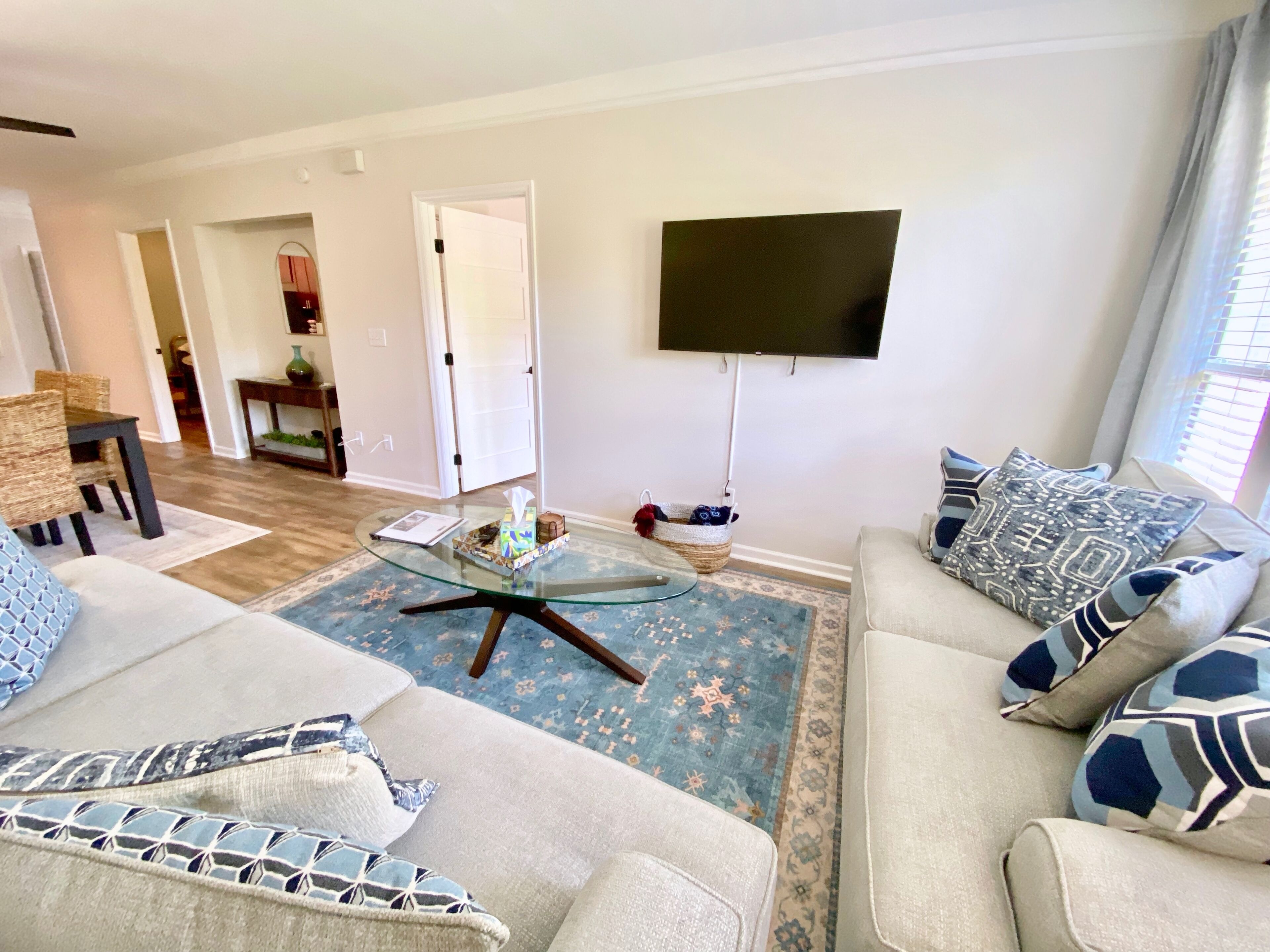 Een woonkamer met een bank, salontafel, flatscreen-tv en een eethoek met stoelen en een tafel.