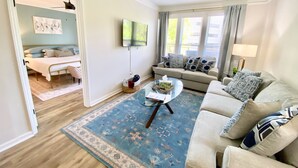 A living room with a sofa, coffee table, and a TV mounted on the wall.