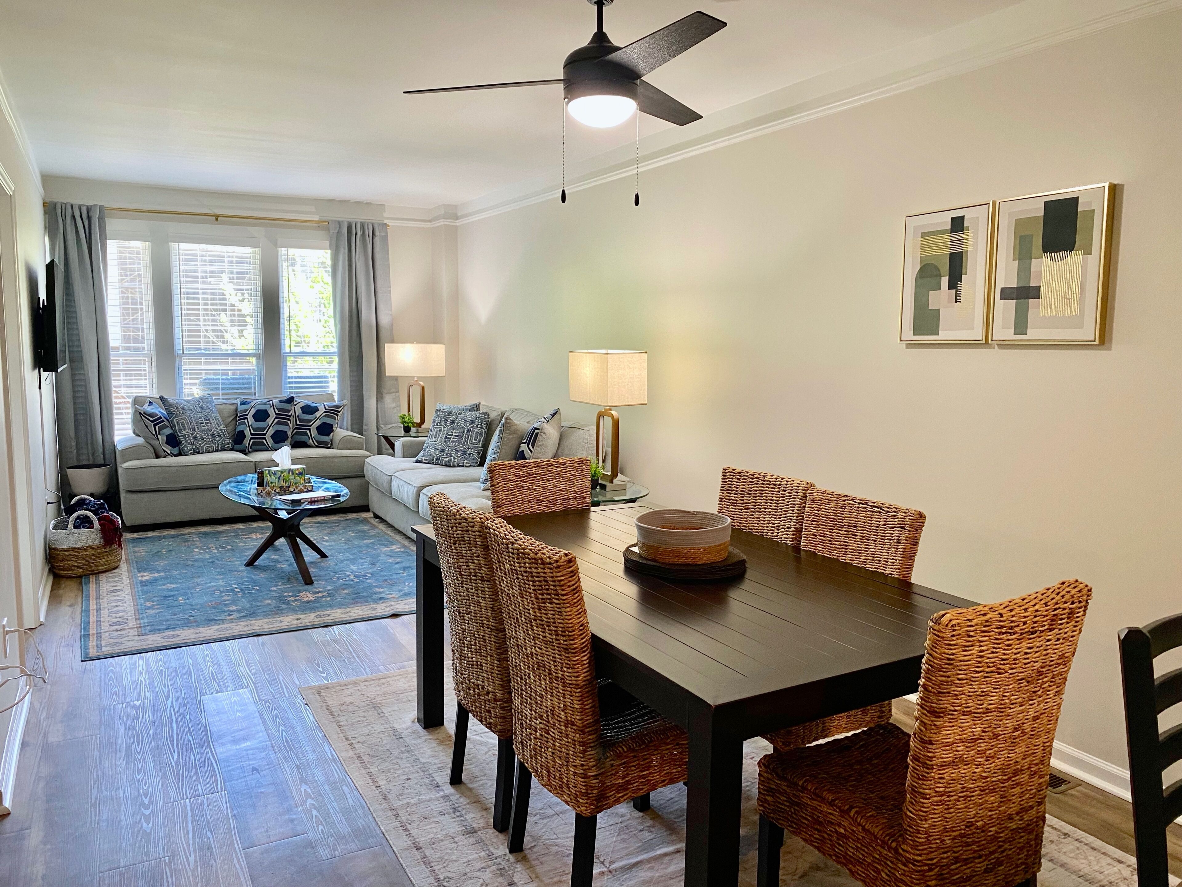 A living room with a sofa, coffee table, and dining table with wicker chairs.