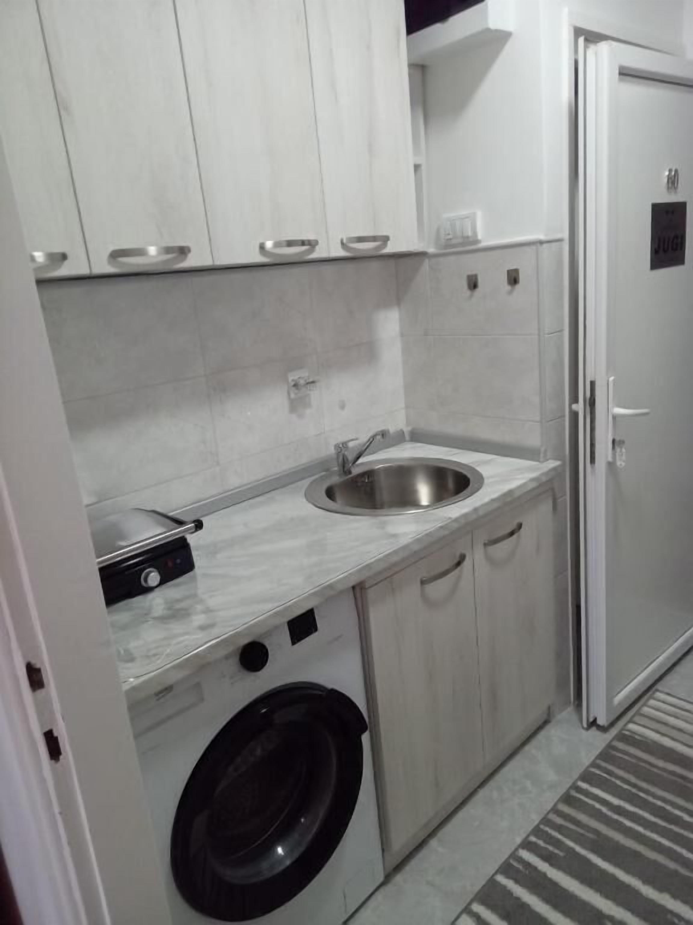 A compact kitchen with a washing machine, a sink, and cabinets.