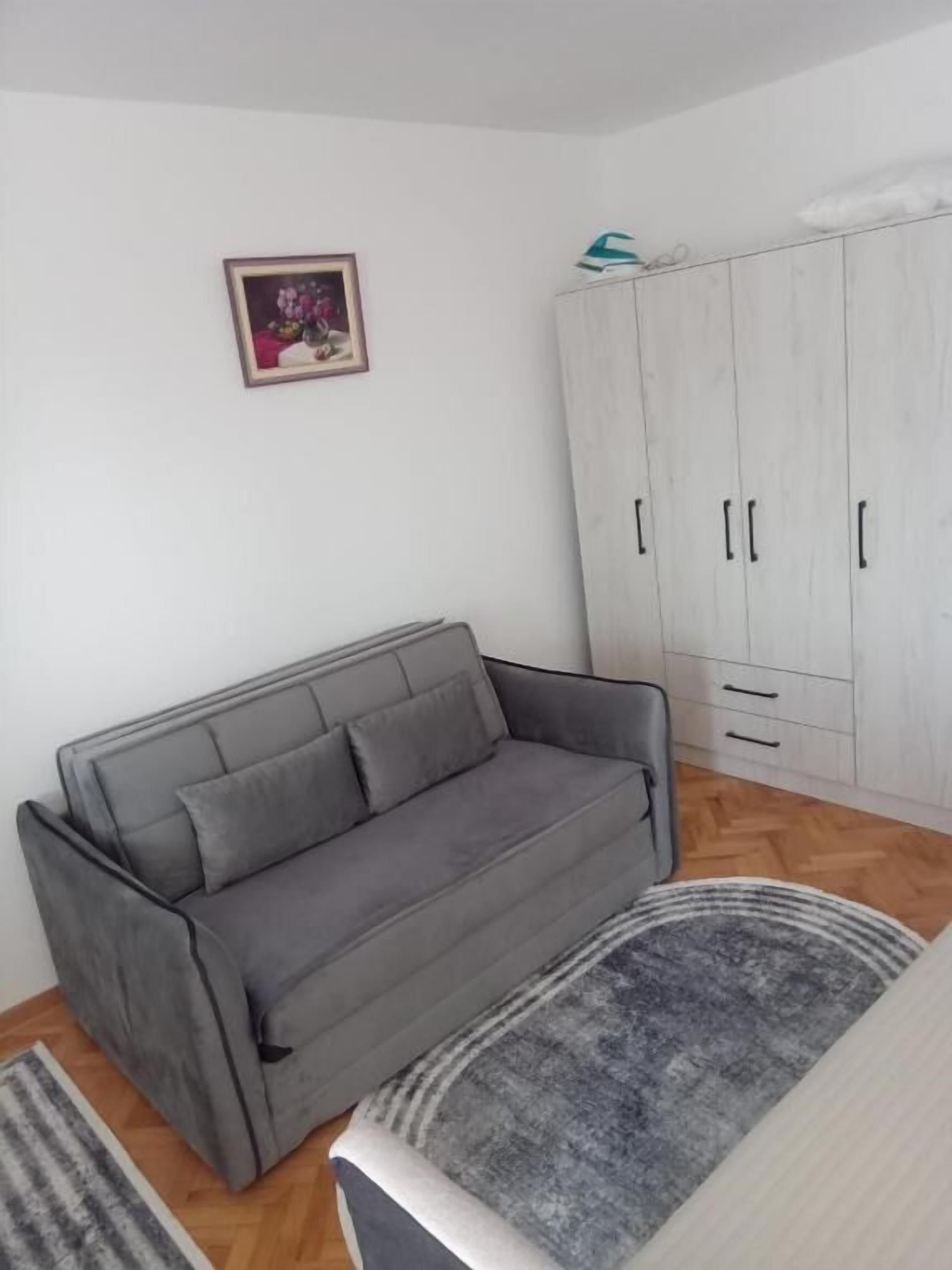 Un canapé gris, une armoire blanche et un tableau encadré au mur.
