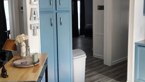 Eine Küche mit einem blauen Schrank, einem Holztisch und einem Mülleimer.