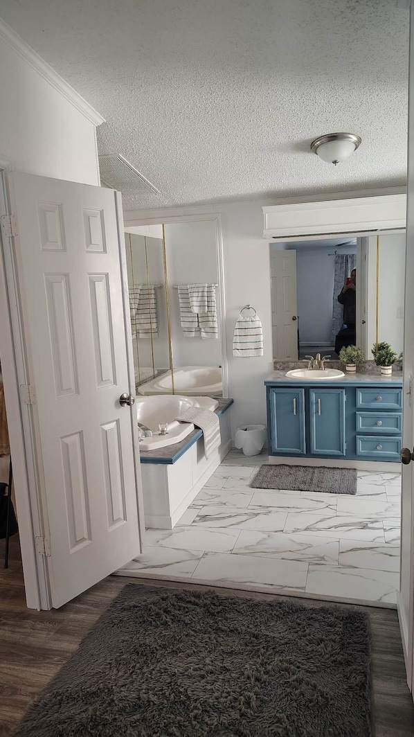 A bathroom with a bathtub, a sink, and a mirror.