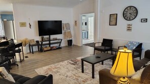 Un salon équipé d’un téléviseur à écran plat, d’une table basse, d’un canapé et d’une lampe.