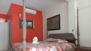 Una cama con dosel y una colcha estampada, un cuadro enmarcado en la pared y una toalla blanca sobre la cama.