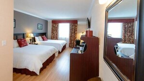 Une chambre d’hôtel avec deux lits, un bureau, un miroir et une télévision.