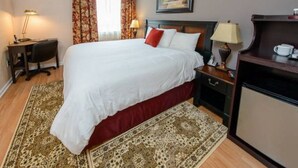 Une chambre d’hôtel avec un grand lit, un bureau, une chaise, une lampe et une machine à café.
