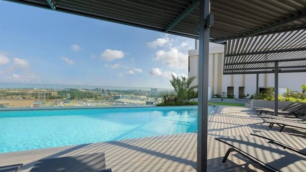 Un espace piscine aménagé sur le toit, avec des chaises longues et une vue sur le panorama urbain.