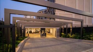 Une entrée moderne d’un bâtiment, avec une passerelle couverte et une personne qui s’en approche.