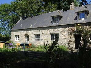 A stone building with a sloped roof, multiple windows, and a small door. - Gite du manoir de Keryvoas 900 m from Boutrouilles beach (Kerlouan)
