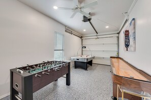 Ein Zimmer mit Fußballtisch, Billardtisch und Deckenventilator.