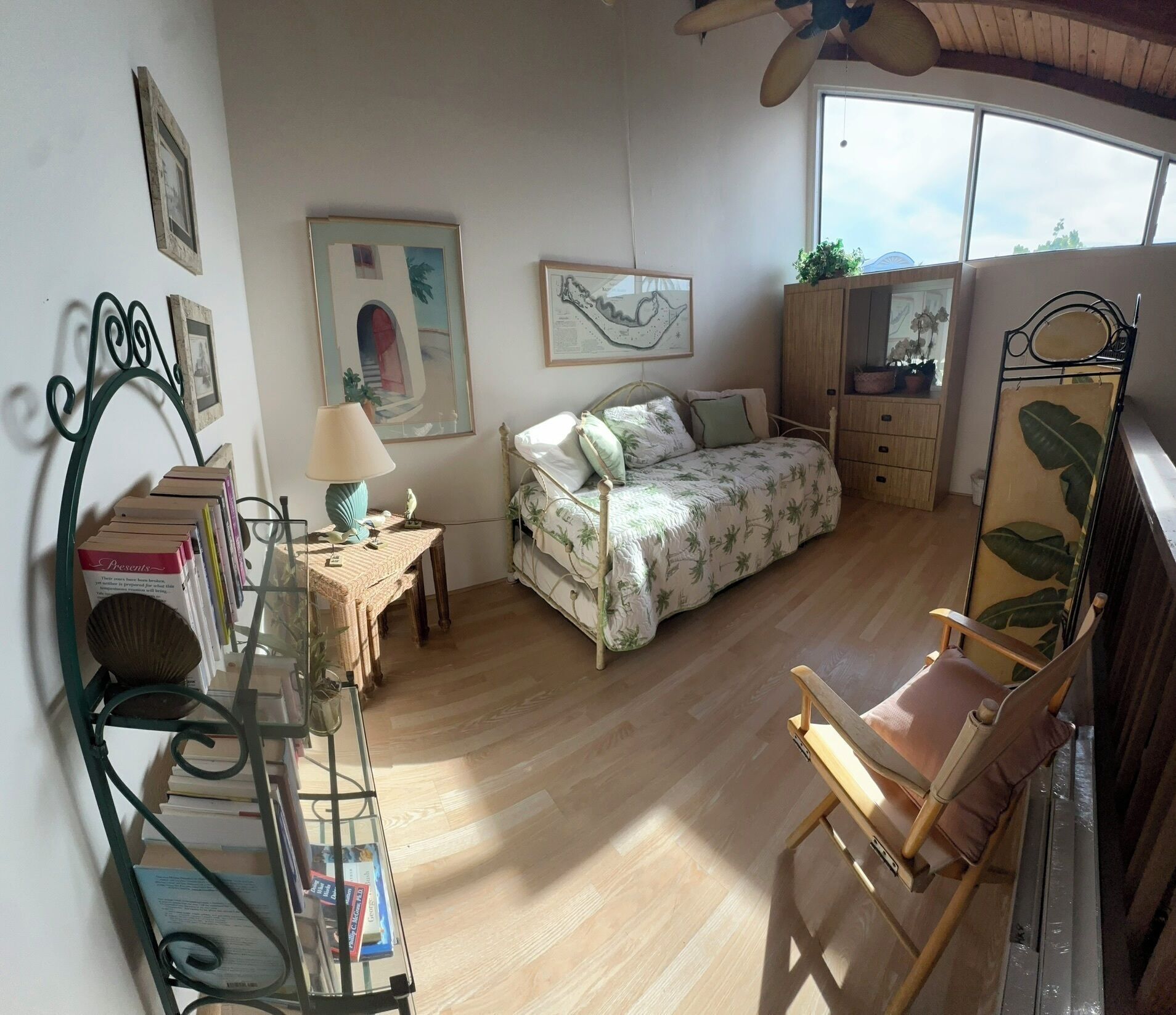 A cozy bedroom with a bed, a chair, a desk with books, and a window.