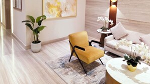 A modern living room with a sofa, armchair, round coffee table, and a potted plant. - Modern Deluxe Studio in Dubai (Al Jaddaf)