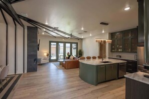 Une cuisine moderne dotée d’un îlot central, de meubles de rangement intégrés et d’un coin repas avec un canapé et des chaises.