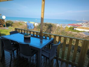 En träveranda med ett bord och stolar med utsikt över havet.
