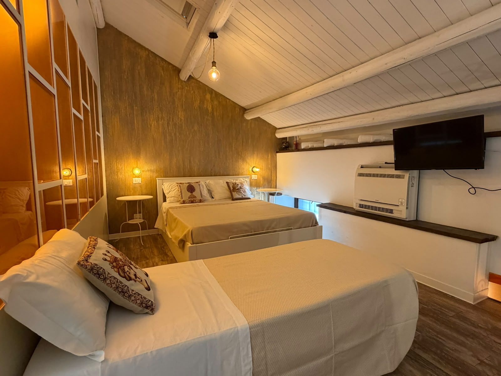 A hotel room with two beds, a television, and an air conditioning unit.