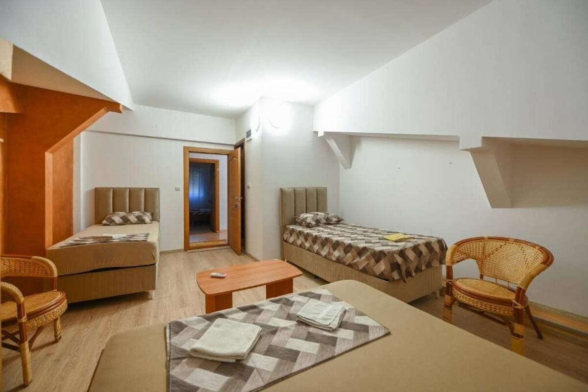 Una habitación compacta con dos camas, un sofá, una mesita y dos sillas de mimbre.